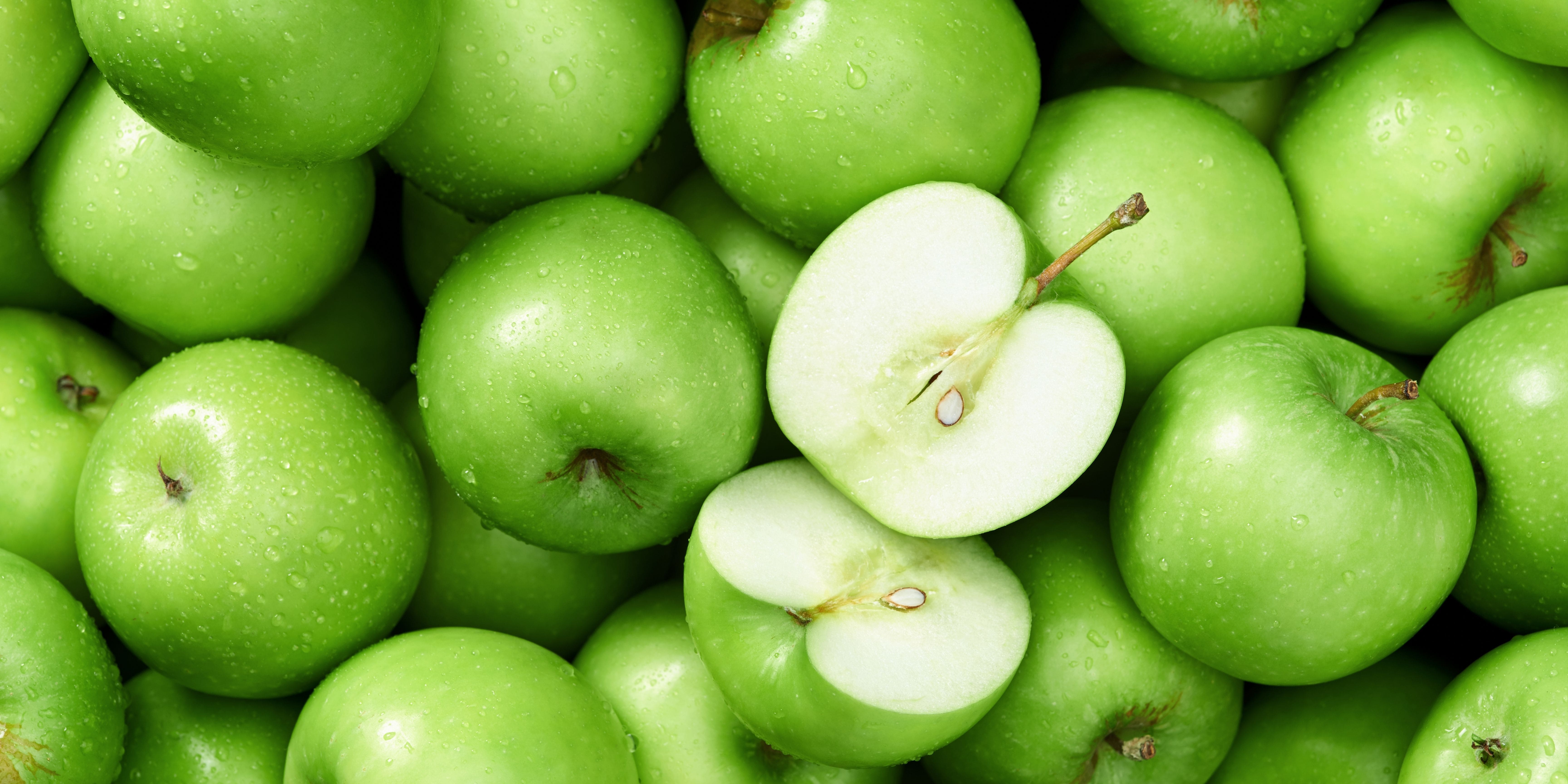 Green apples being stored with one apple cut open