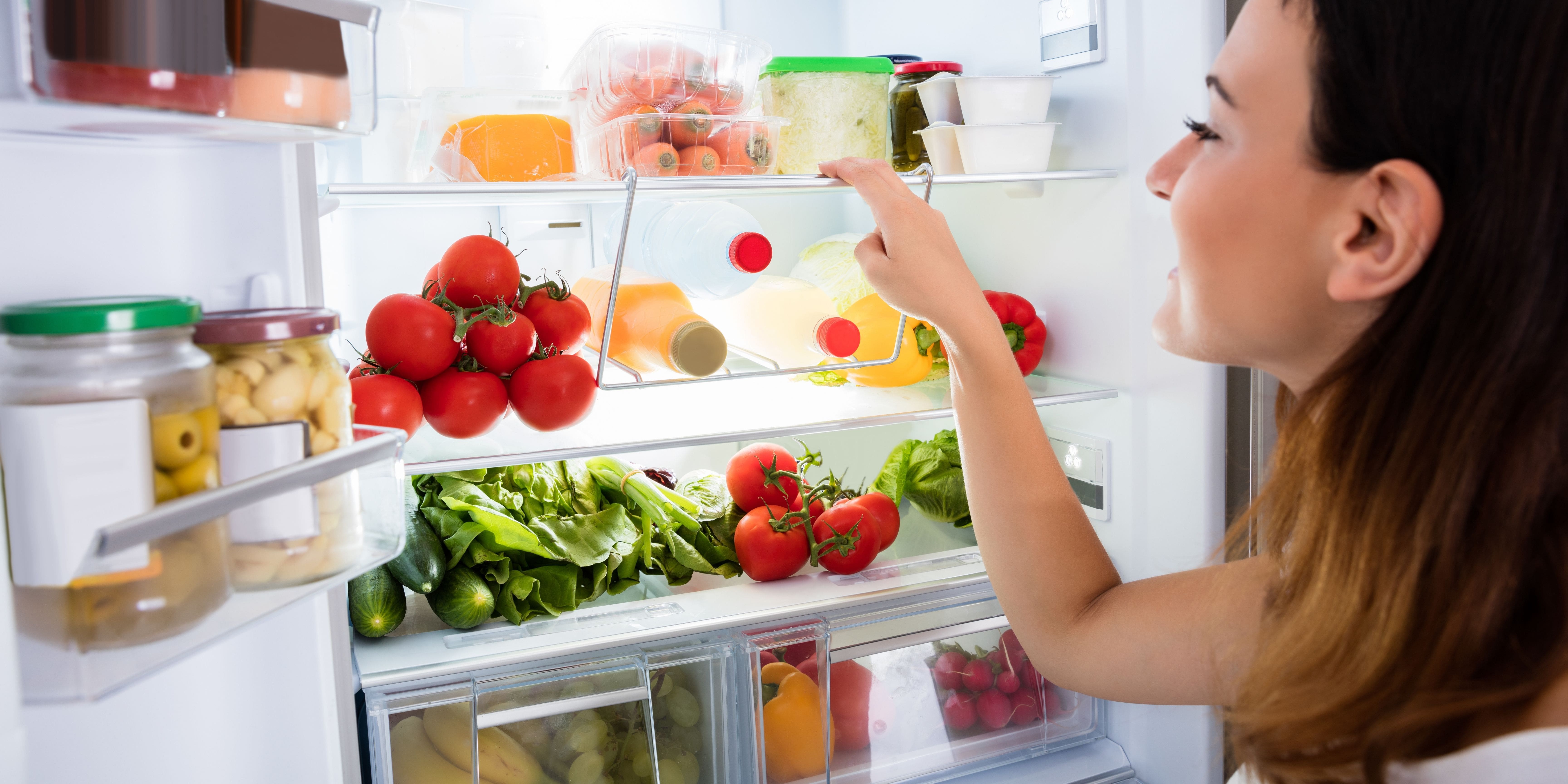 Woman looking into fridge at fresh produce being stored